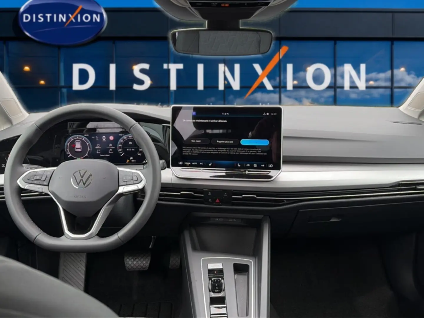 Vue intérieure avant du tableau de bord et volant gris clair d'une Volkswagen Golf 2026 avec écran tactile central et affichage numérique.