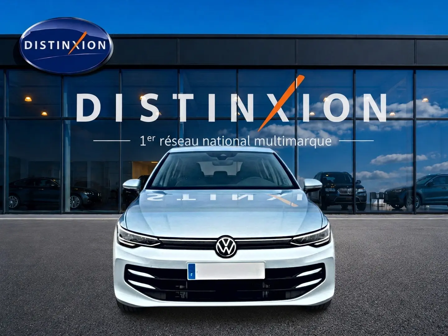 Vue avant d'une Volkswagen Golf 1.5 ETSI Evo2 bleu glacier garée devant une vitrine Distinxion.