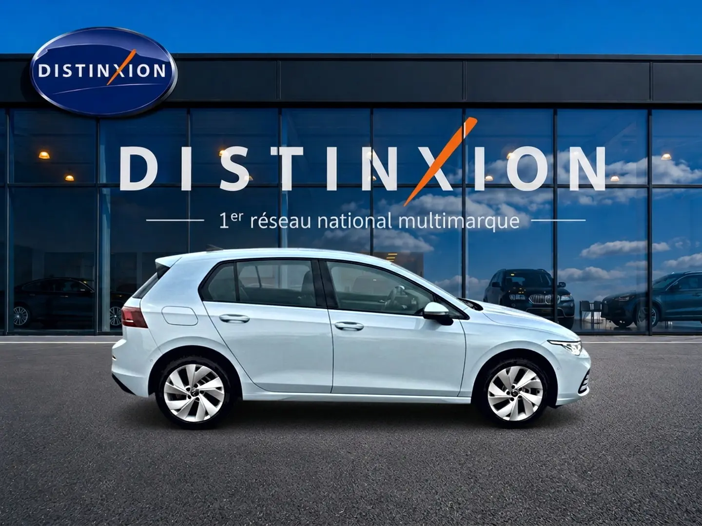 Volkswagen Golf 2026 bleu glacier vue de profil côté gauche devant une vitrine Distinxion.