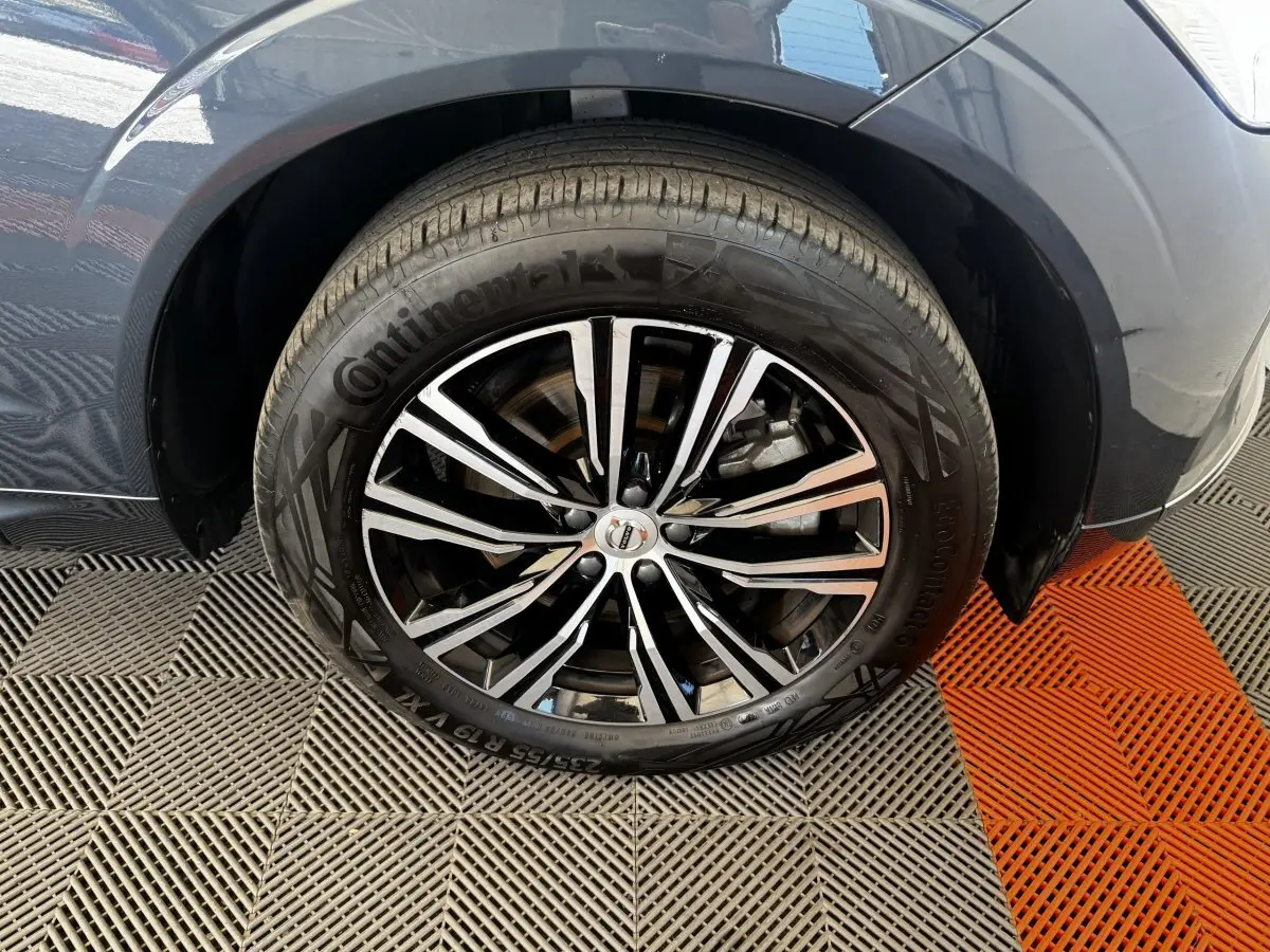 Gros plan sur la roue avant droite du Volvo XC60 bleu, mettant en valeur la jante alliage noire et argentée.