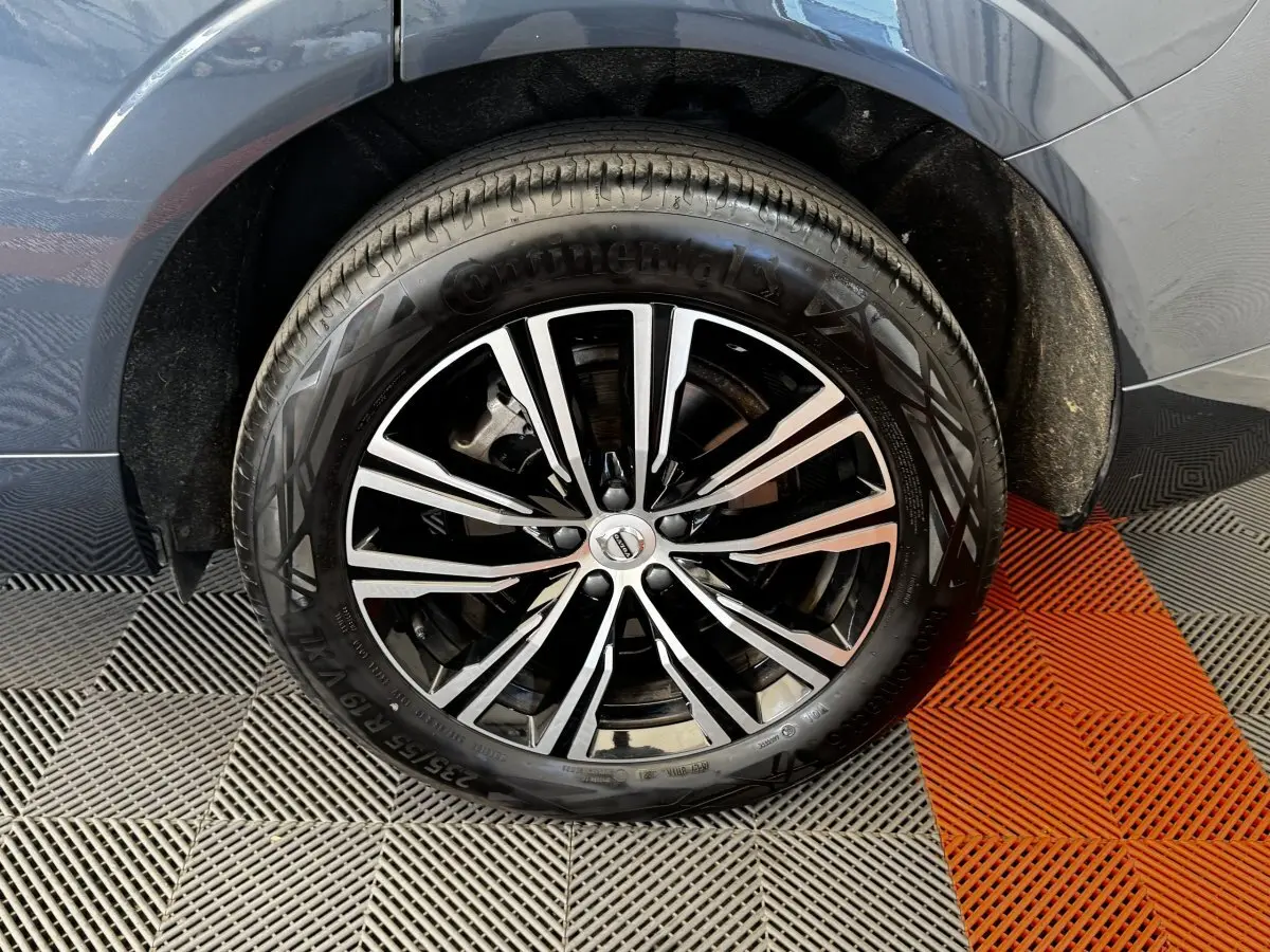 Gros plan sur la roue avant droite avec jante alliage bicolore du Volvo XC60 bleu hybride rechargeable.