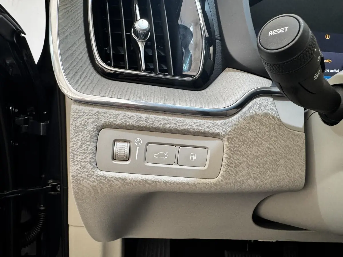 Détail intérieur côté gauche du tableau de bord beige clair du Volvo XC60 bleu avec commandes ouverture coffre et réservoir.