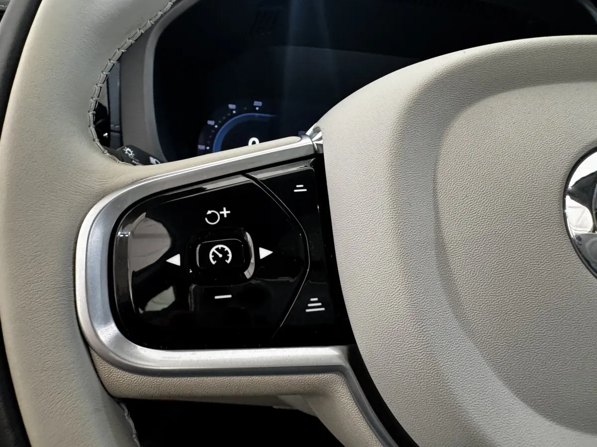 Gros plan sur les commandes de régulateur de vitesse à gauche du volant beige du Volvo XC60 Recharge T8 2021.