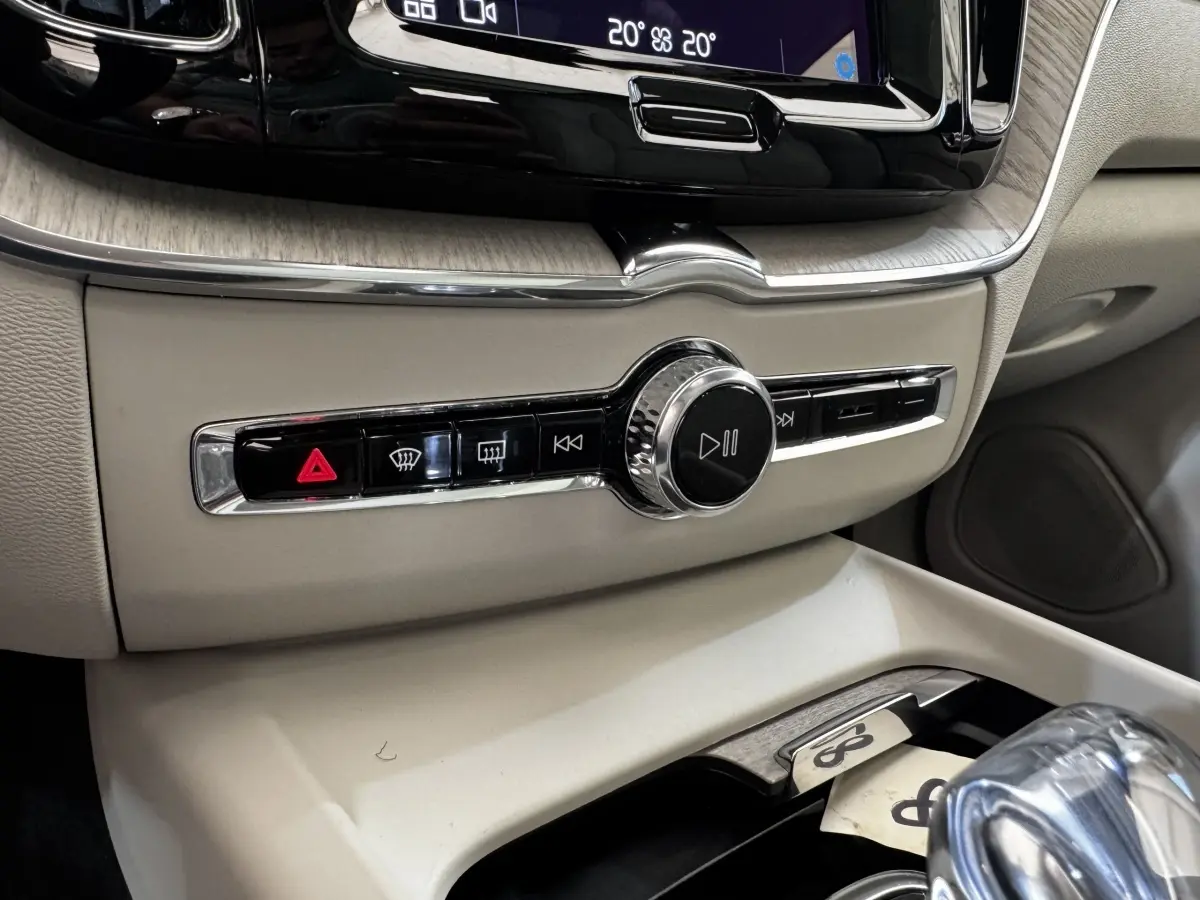 Gros plan sur la console centrale beige du Volvo XC60 bleu, avec commandes multimédia et climatisation visibles.