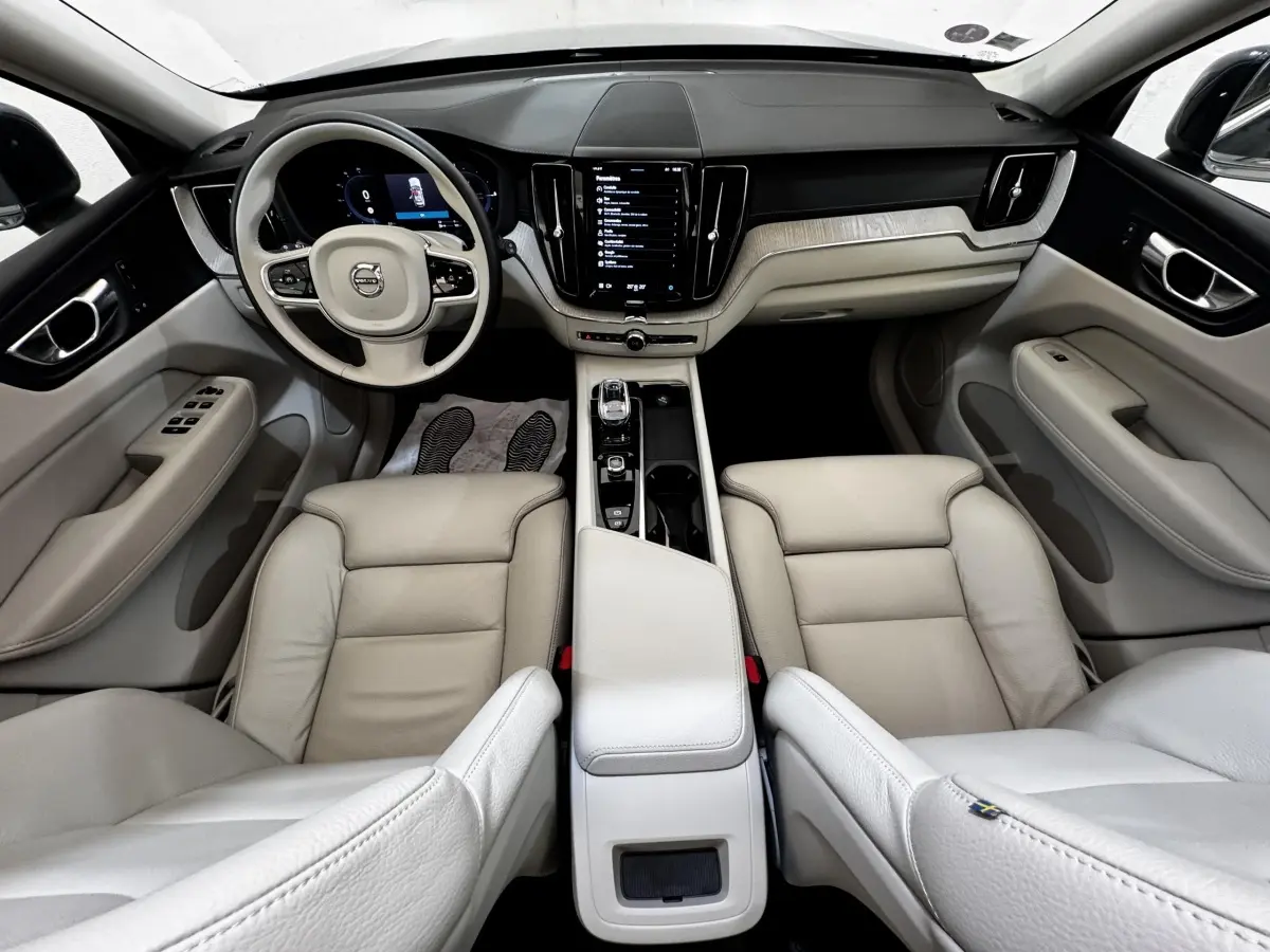 Intérieur clair du Volvo XC60 Recharge T8 2021, vue avant centrée sur tableau de bord et sièges cuir beige.