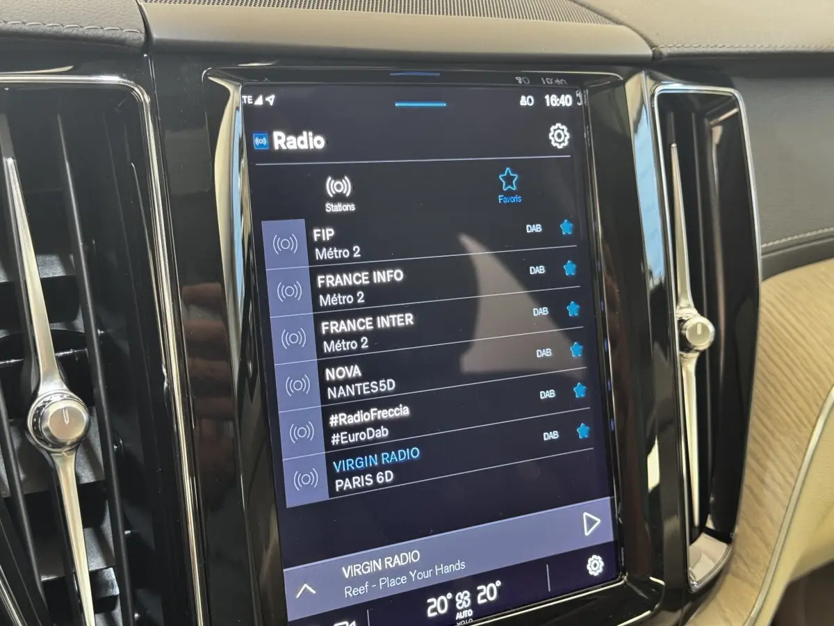 Écran tactile central du tableau de bord du Volvo XC60 bleu, affichant les stations radio numériques.