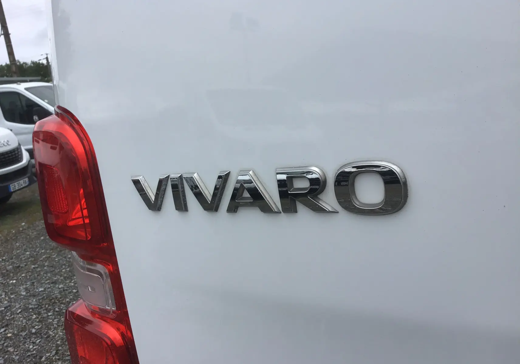 Gros plan sur l'arrière gauche blanc d'un Opel Vivaro 2022 avec logo chromé et feu arrière rouge visible.
