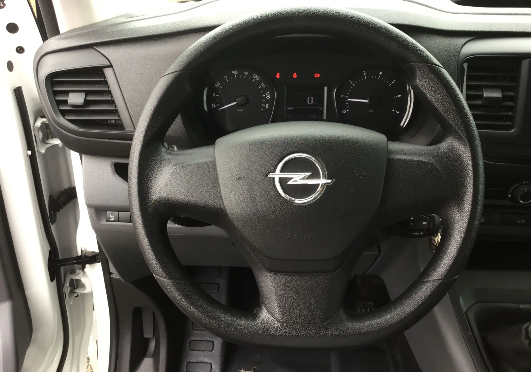 Vue rapprochée du volant noir d'un Opel Vivaro blanc 2022, avec tableau de bord et compteur digital visibles.