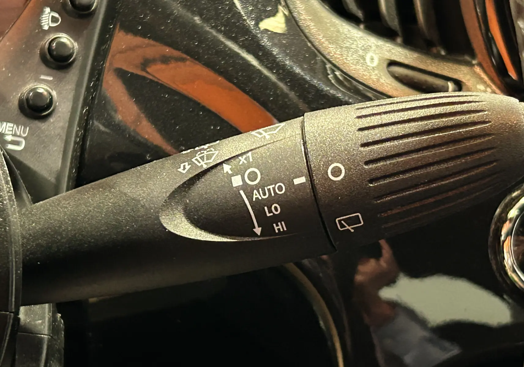 Gros plan sur la commande d'essuie-glace noire dans l'habitacle d'une Fiat 500 noire 2023 version Pack Confort.