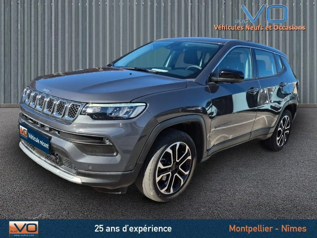Jeep Compass gris 3/4 avant droit, jantes alliage 18 pouces, calandre distinctive et phares LED visibles.