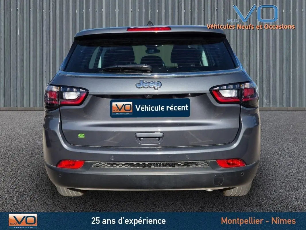 Vue arrière d'un Jeep Compass gris 2024 avec feux LED et logo Jeep bien visibles sur un fond urbain.