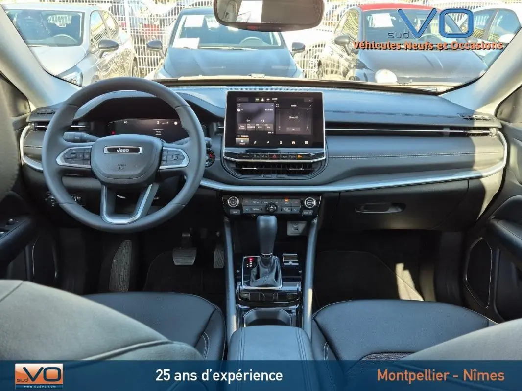 Intérieur du Jeep Compass 2024 en vue frontale, tableau de bord noir avec écran tactile central et volant multifonction.