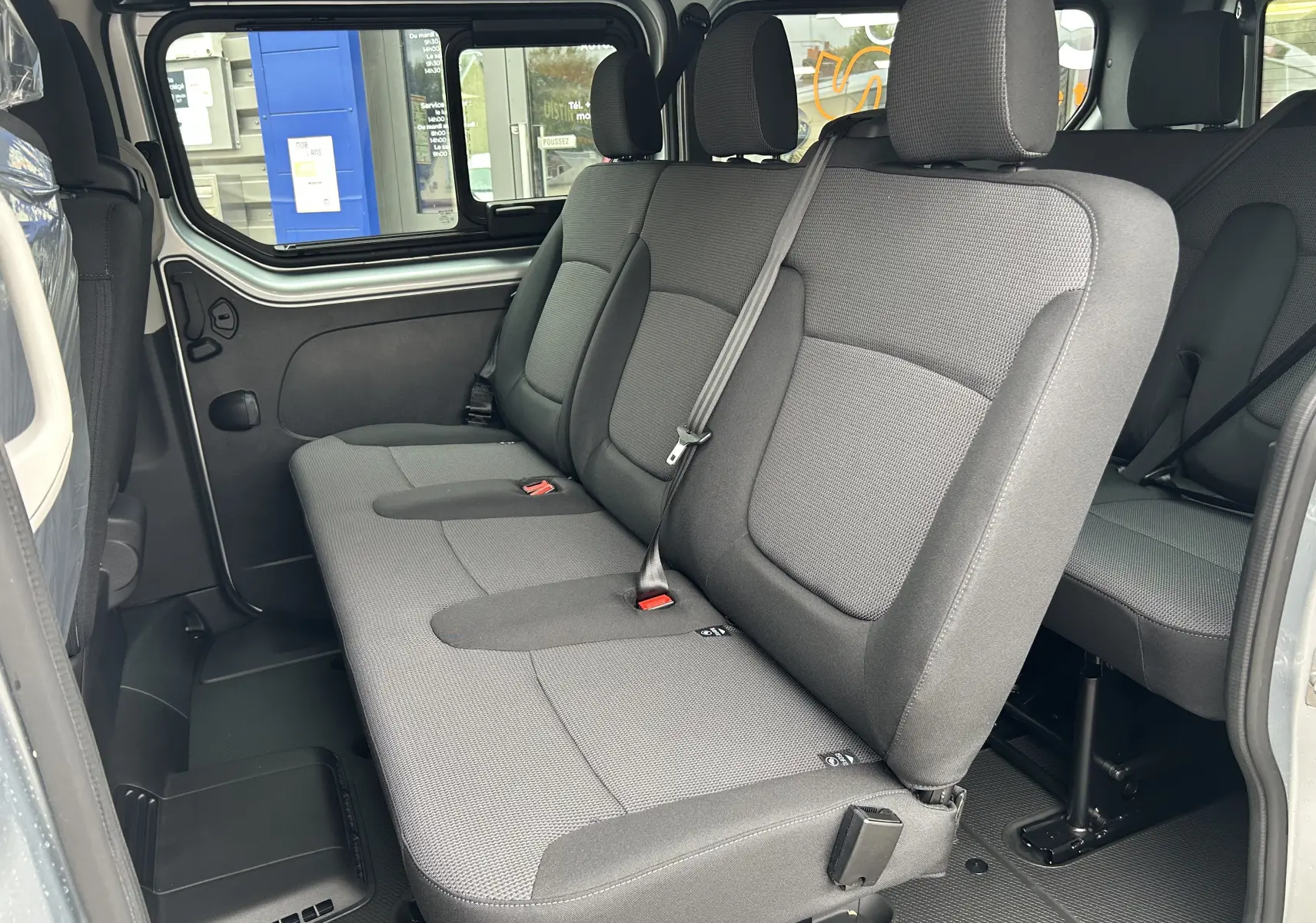 Vue intérieure côté gauche sur la banquette arrière grise du Renault Trafic Combi L2 Grand Evolution 2025 avec porte coulissante ouverte.