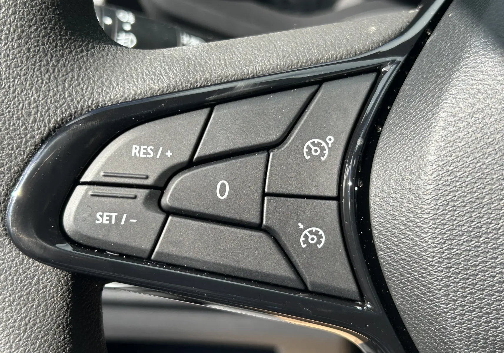 Gros plan sur les commandes de régulateur de vitesse au volant du Renault Trafic Combi blanc Glacier 2025.