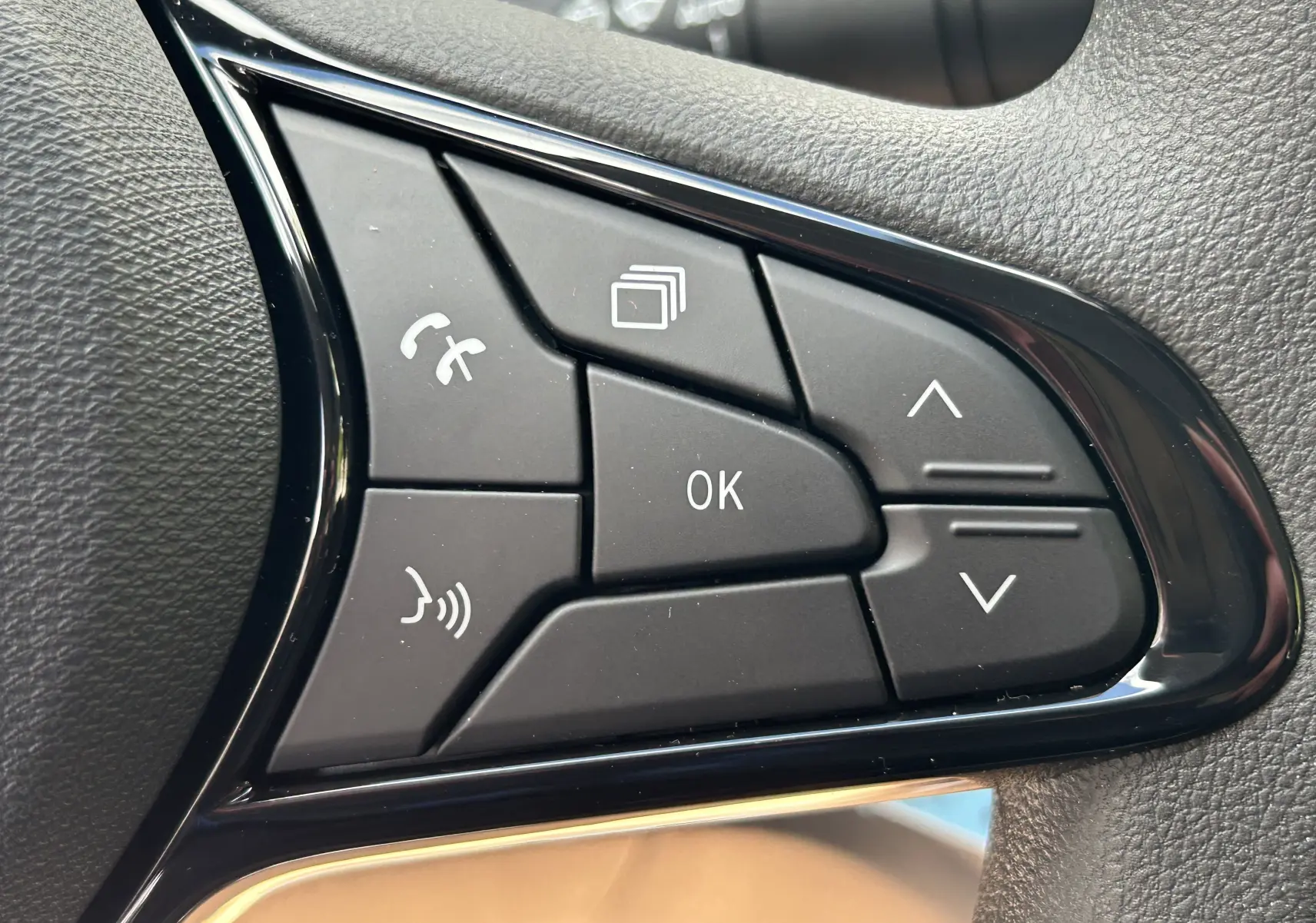 Gros plan sur les commandes multifonctions au volant du Renault Trafic Combi 2025, finition noire texturée.