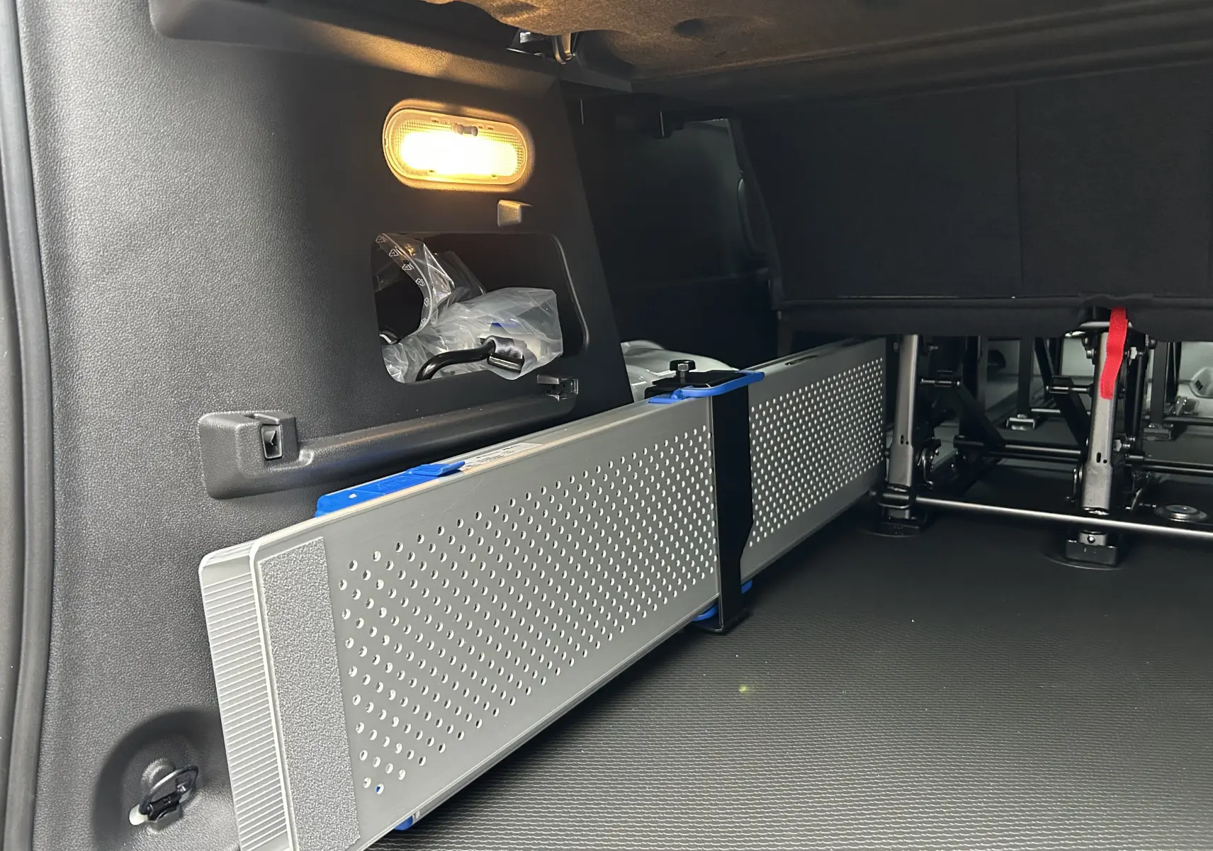 Vue intérieure arrière droite du Renault Trafic Combi blanc glacier, montrant le rangement sous banquette et l'éclairage intérieur.