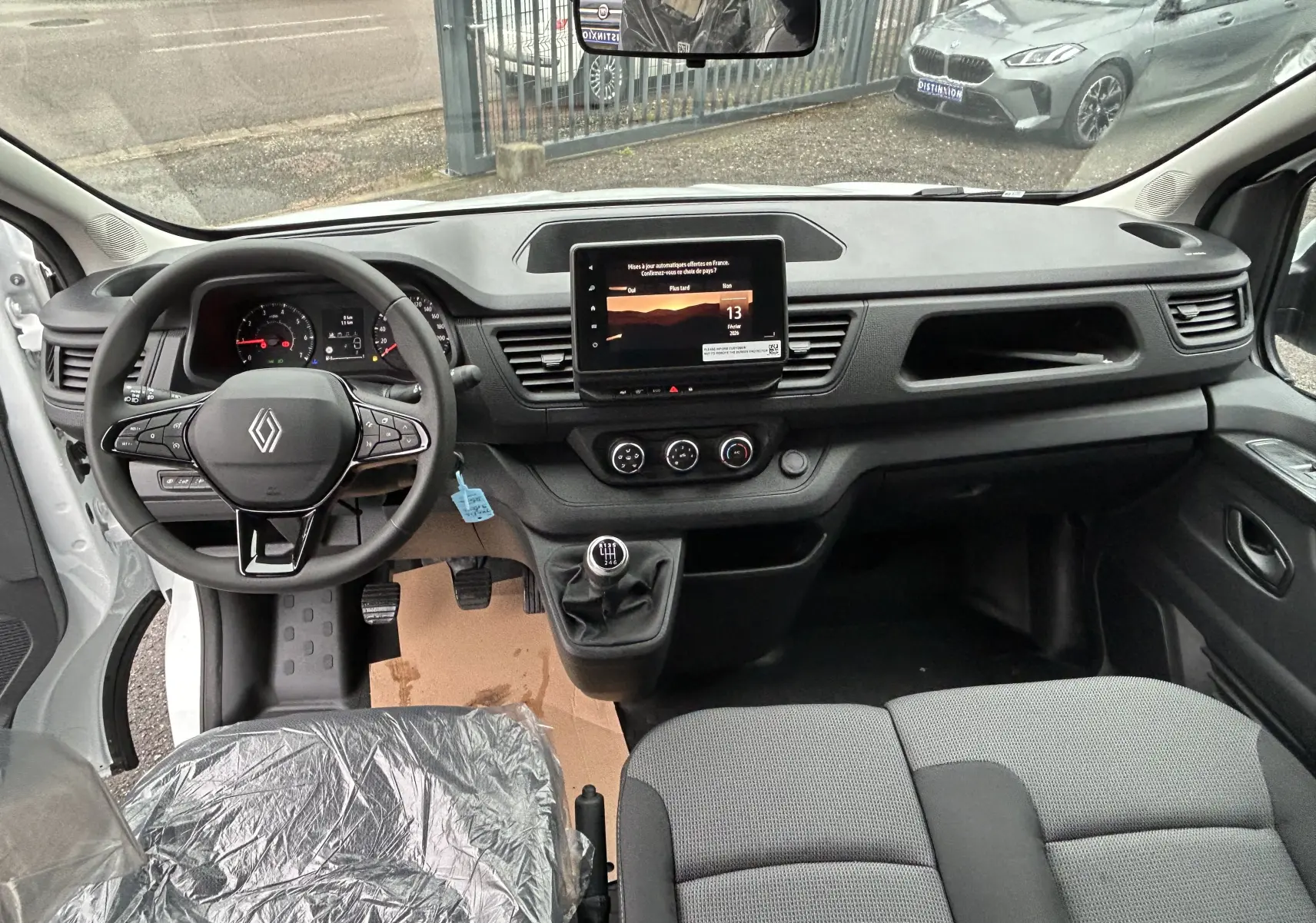 Vue intérieure avant du Renault Trafic Combi blanc Glacier 2025, tableau de bord avec écran tactile et volant multifonction.