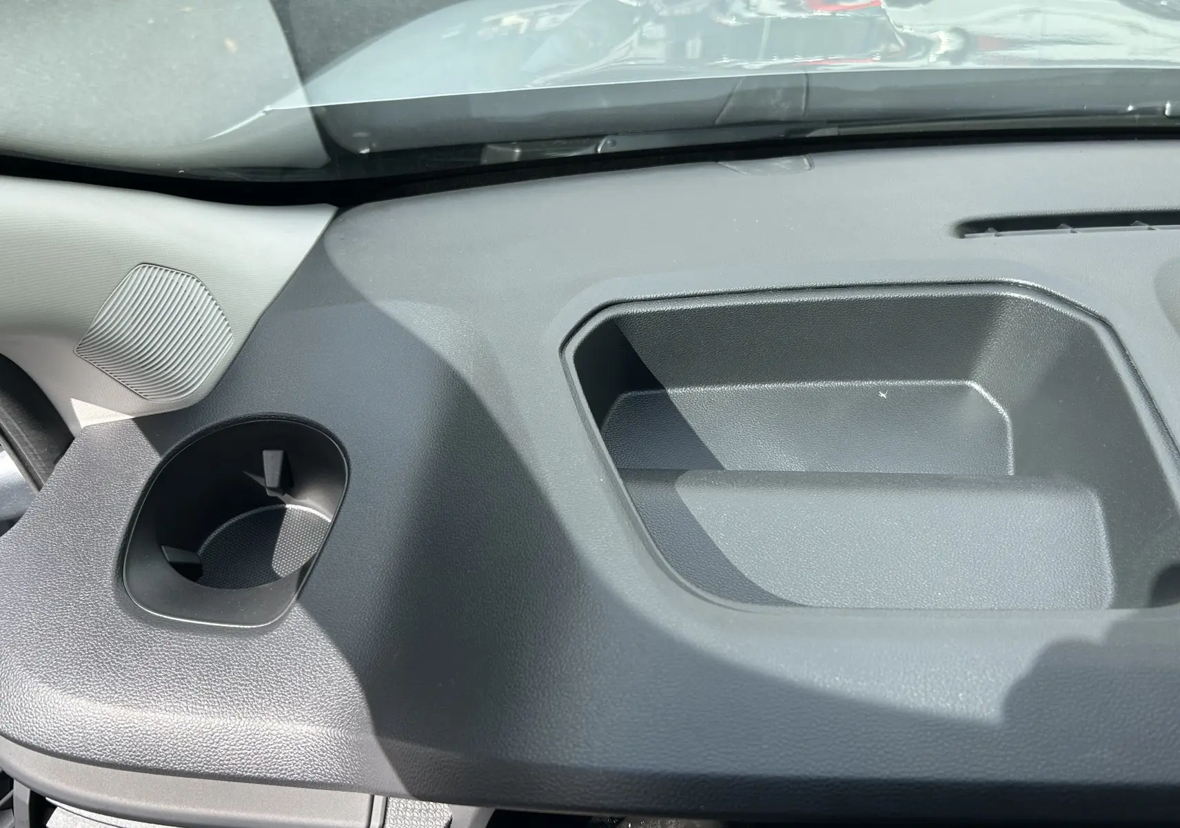 Détail intérieur du tableau de bord gris foncé du Renault Trafic Combi, avec porte-gobelet et rangement intégré.