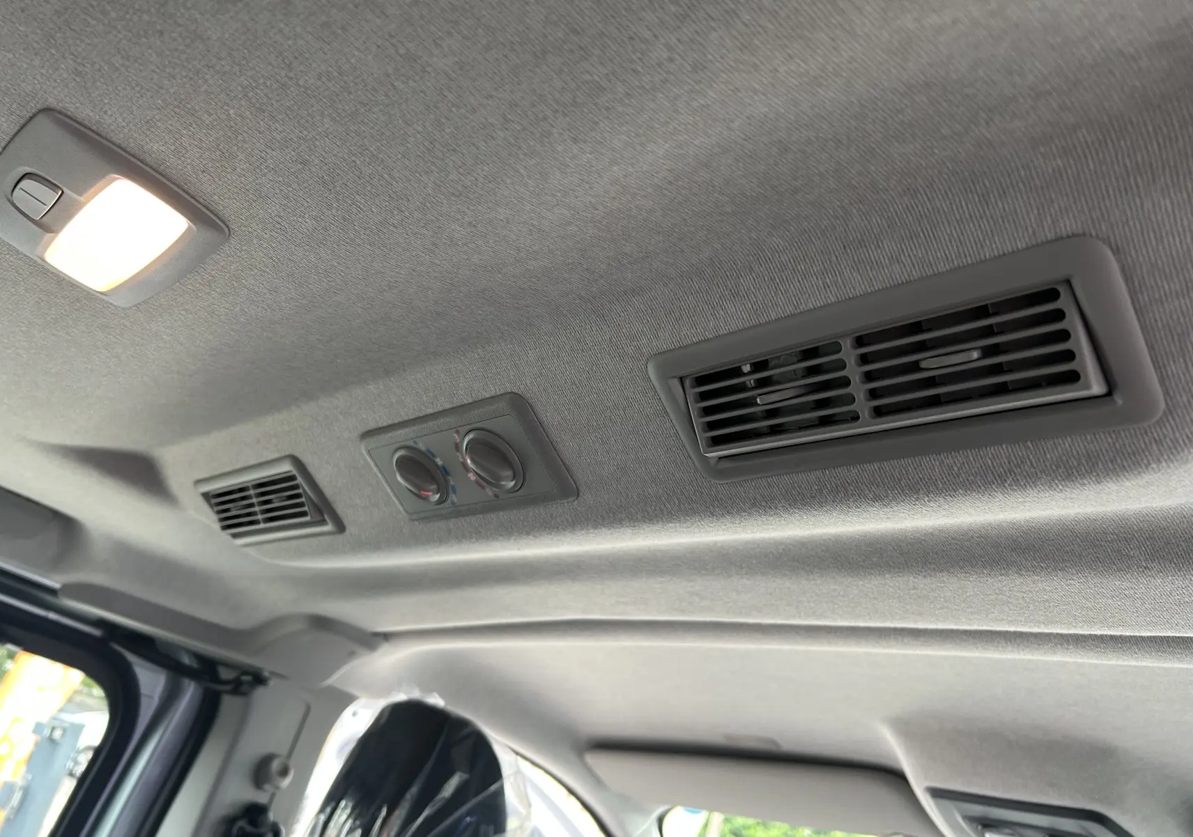 Plafond intérieur gris du Renault Trafic Combi L2 Grand Evolution 2025 avec aérateurs et commandes de climatisation arrière.