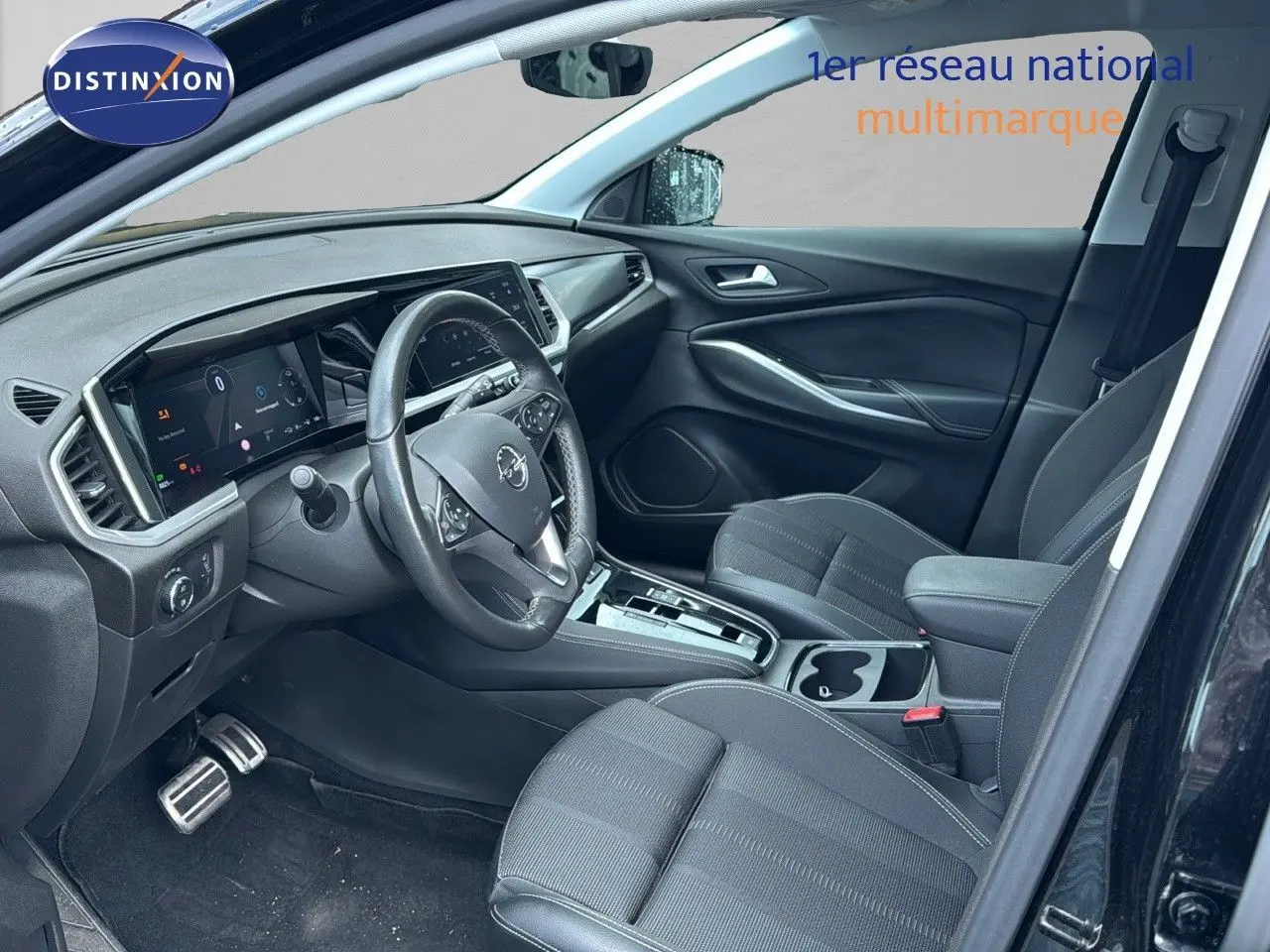 Intérieur avant droit de l’Opel Grandland noir 2024, montrant tableau de bord numérique et sièges tissu noir.