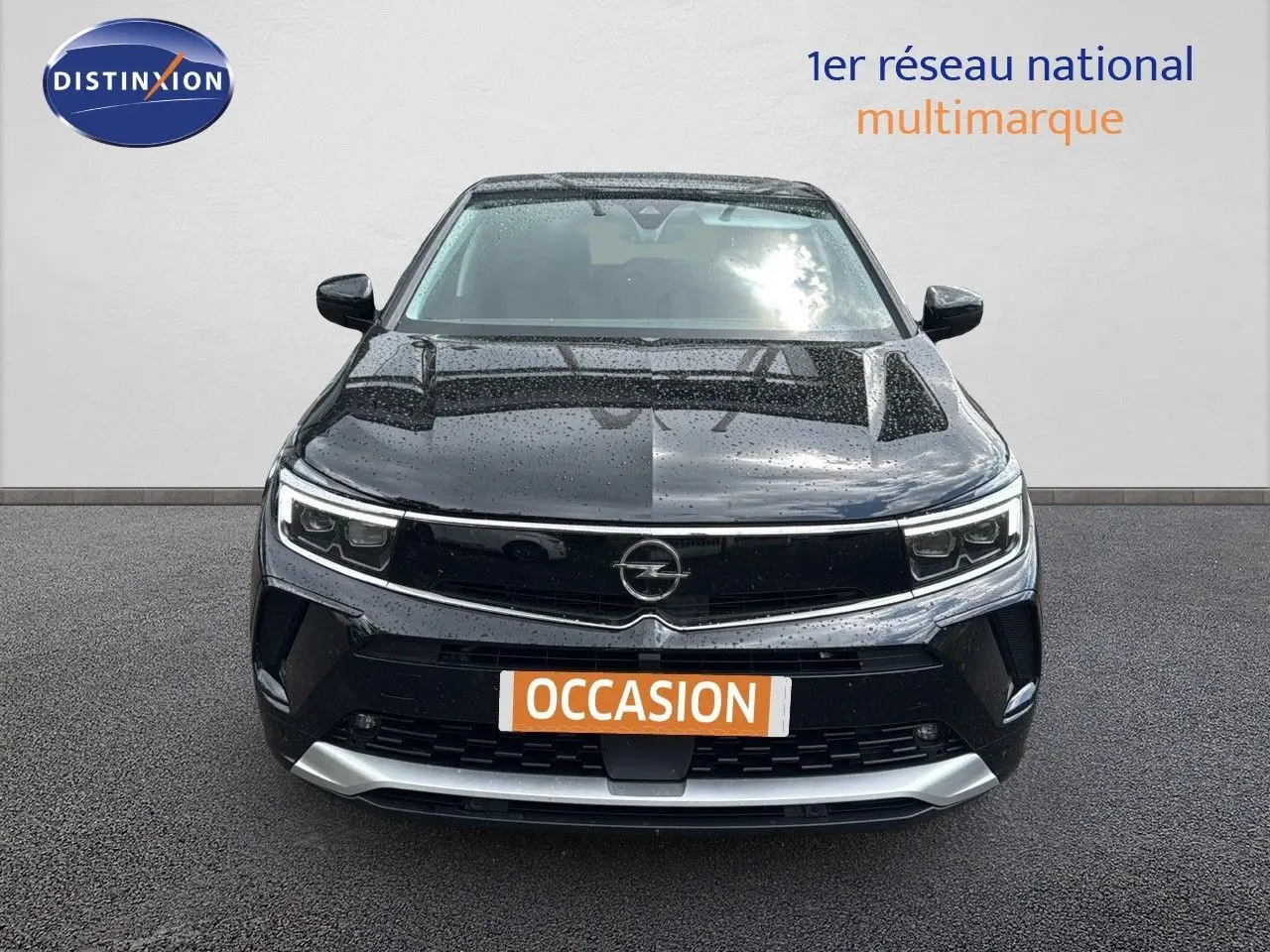 Vue de face d'un Opel Grandland 1.6 Turbo Hybrid 225ch GS noir, avec calandre et phares LED sous la pluie.