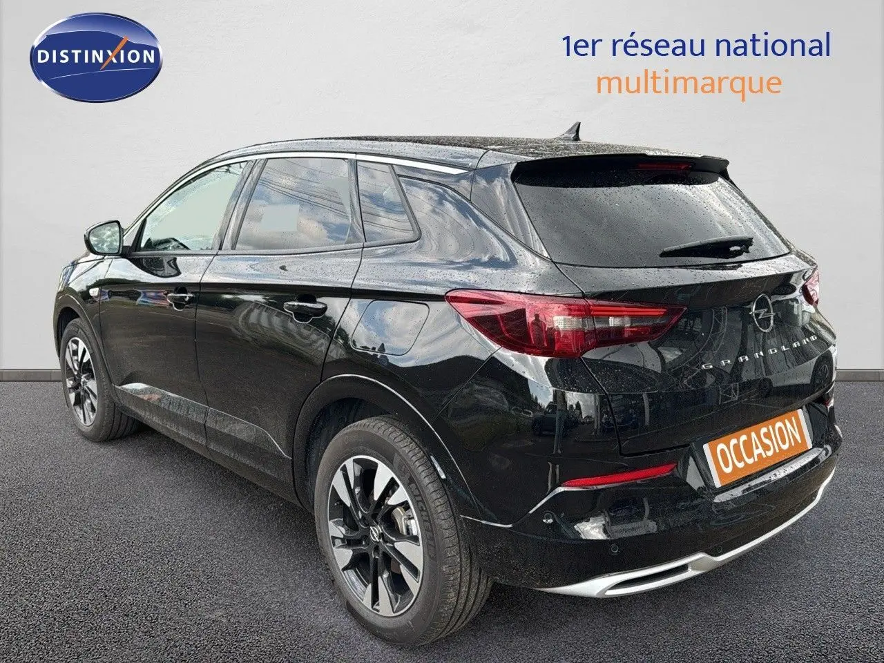 Opel Grandland noir vue 3/4 arrière droit, hybride rechargeable, jantes bi-ton et feux arrière LED visibles.