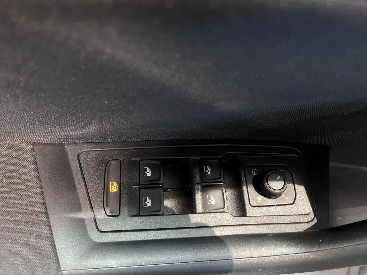 Gros plan sur les commandes de lève-vitres et réglage des rétroviseurs côté conducteur d’un Volkswagen T-Roc noir.