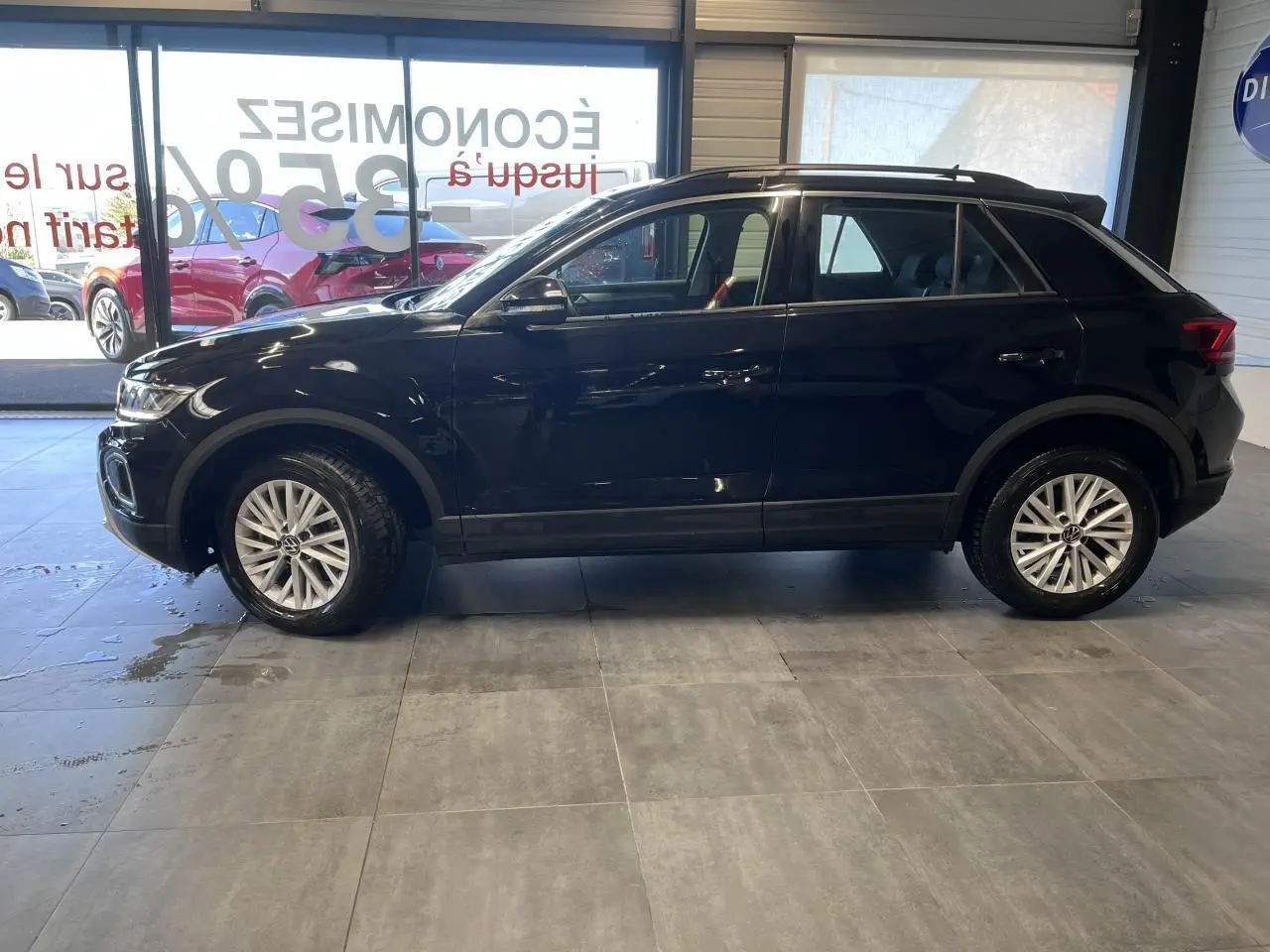 Profil côté gauche d'un Volkswagen T-Roc 2025 noir Deep Black Pearlescent avec jantes alliage et vitres teintées.