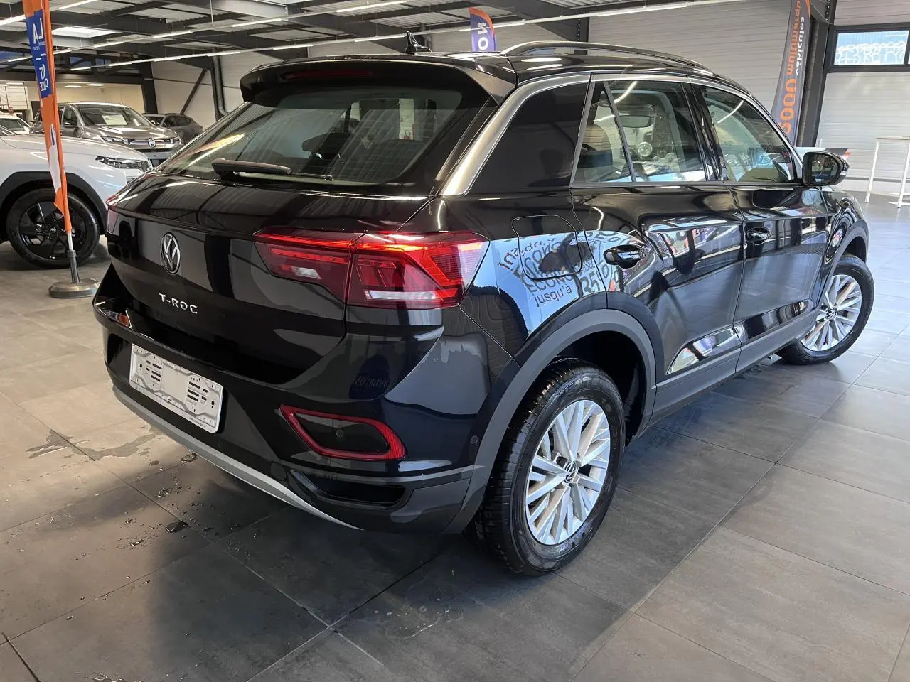 Vue 3/4 arrière droit du Volkswagen T-Roc Deep Black Pearlescent avec jantes alliage et feux LED rouges.