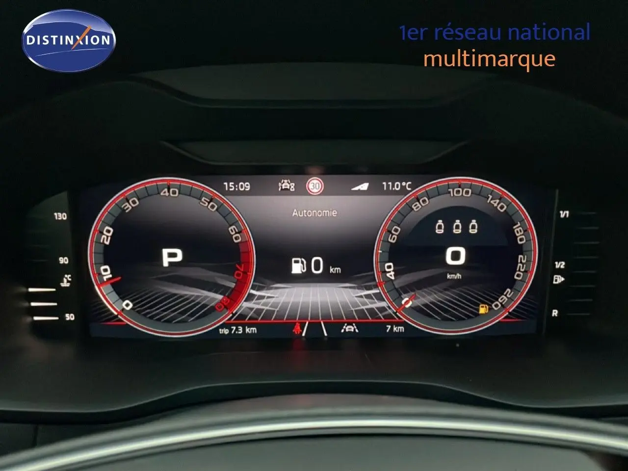 Tableau de bord numérique du Skoda Karoq gris argent, affichant vitesse et autonomie à 0 km, vue frontale rapprochée.