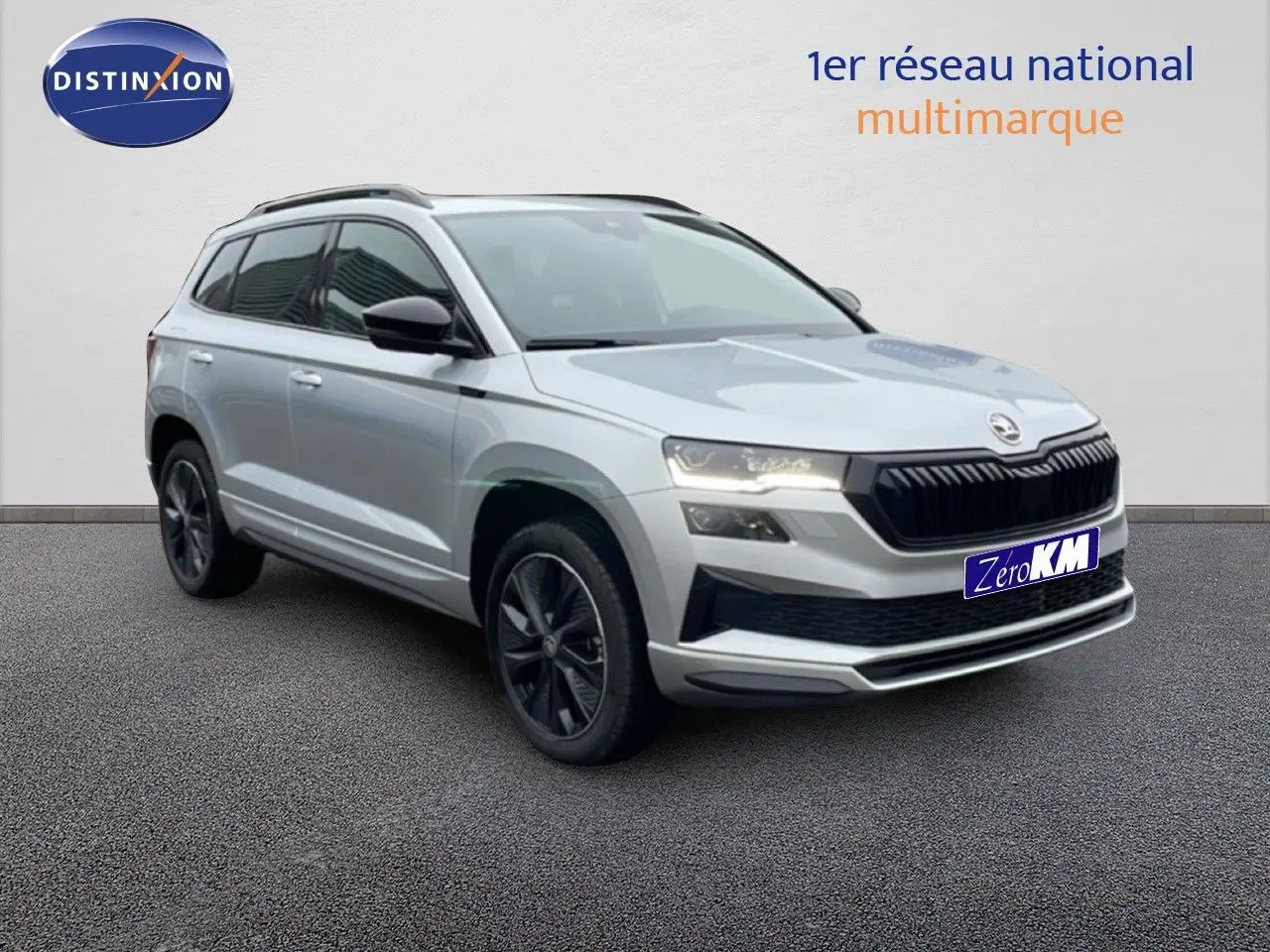 SKODA KAROQ 1.5 TSI 2025 gris argent métal, vue 3/4 avant droit avec calandre noire et jantes foncées.