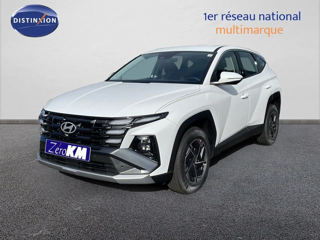 Hyundai Tucson blanc atlas en 3/4 avant droit, avec calandre noire et jantes bi-ton distinctives.