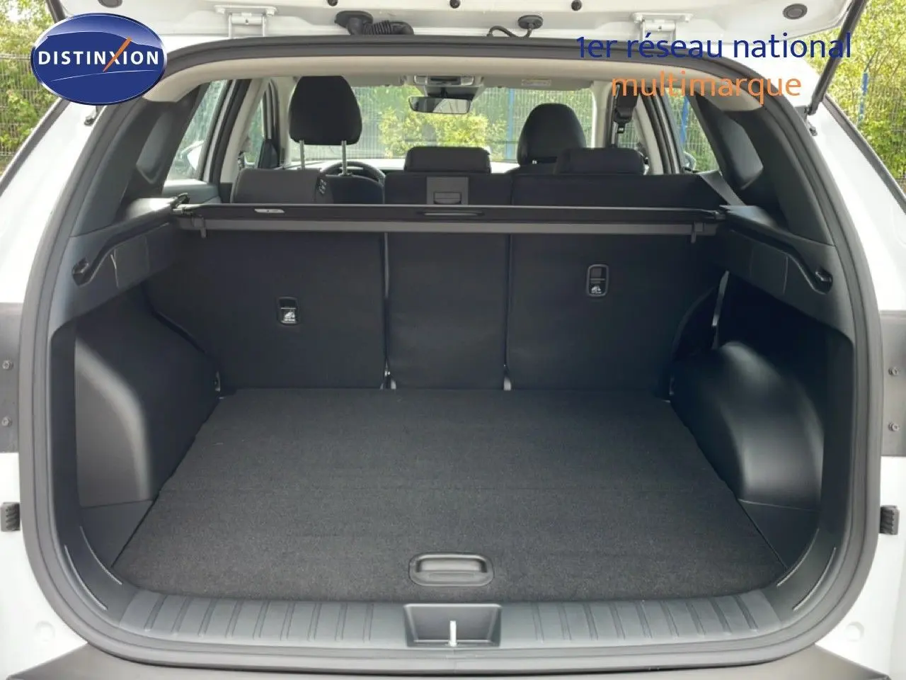 Coffre ouvert d’un Hyundai Tucson blanc Atlas 2026, montrant un espace de chargement propre et spacieux avec cache-bagages.