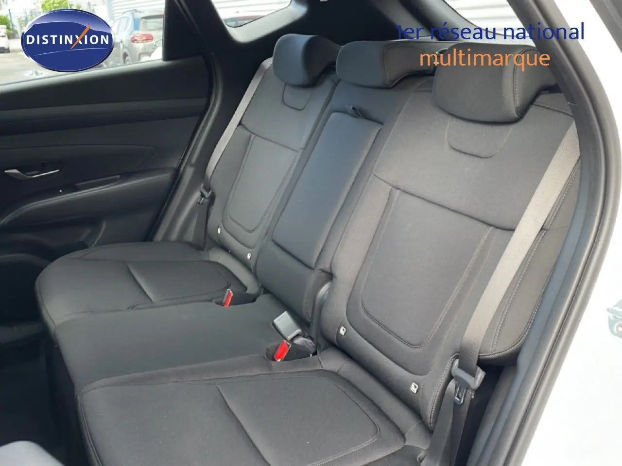 Vue intérieure montrant les sièges arrière en tissu noir du Hyundai Tucson blanc Atlas, avec ceinture de sécurité visible côté droit.