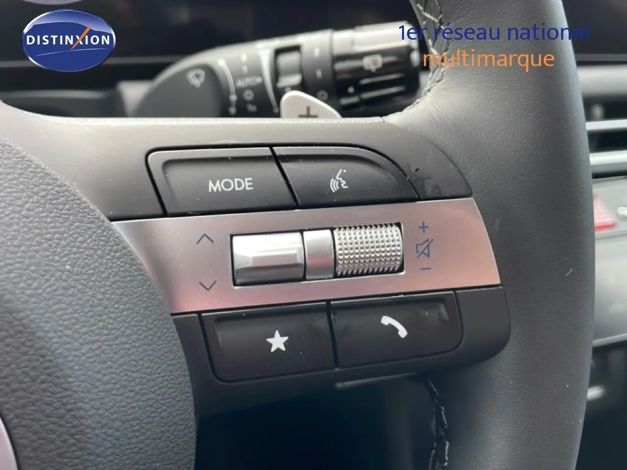 Gros plan sur les commandes multifonctions du volant en cuir noir du Hyundai Tucson blanc, avec molette et boutons tactiles.