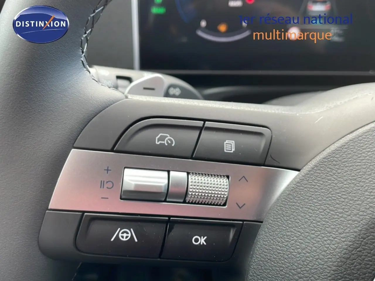Gros plan sur les commandes au volant du Hyundai Tucson blanc Atlas, mettant en valeur les boutons multifonctions et la molette argentée.
