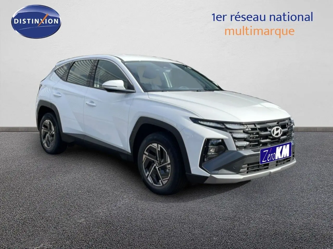 Hyundai Tucson blanc atlas en 3/4 avant droit, avec calandre noire distinctive et jantes bi-ton.