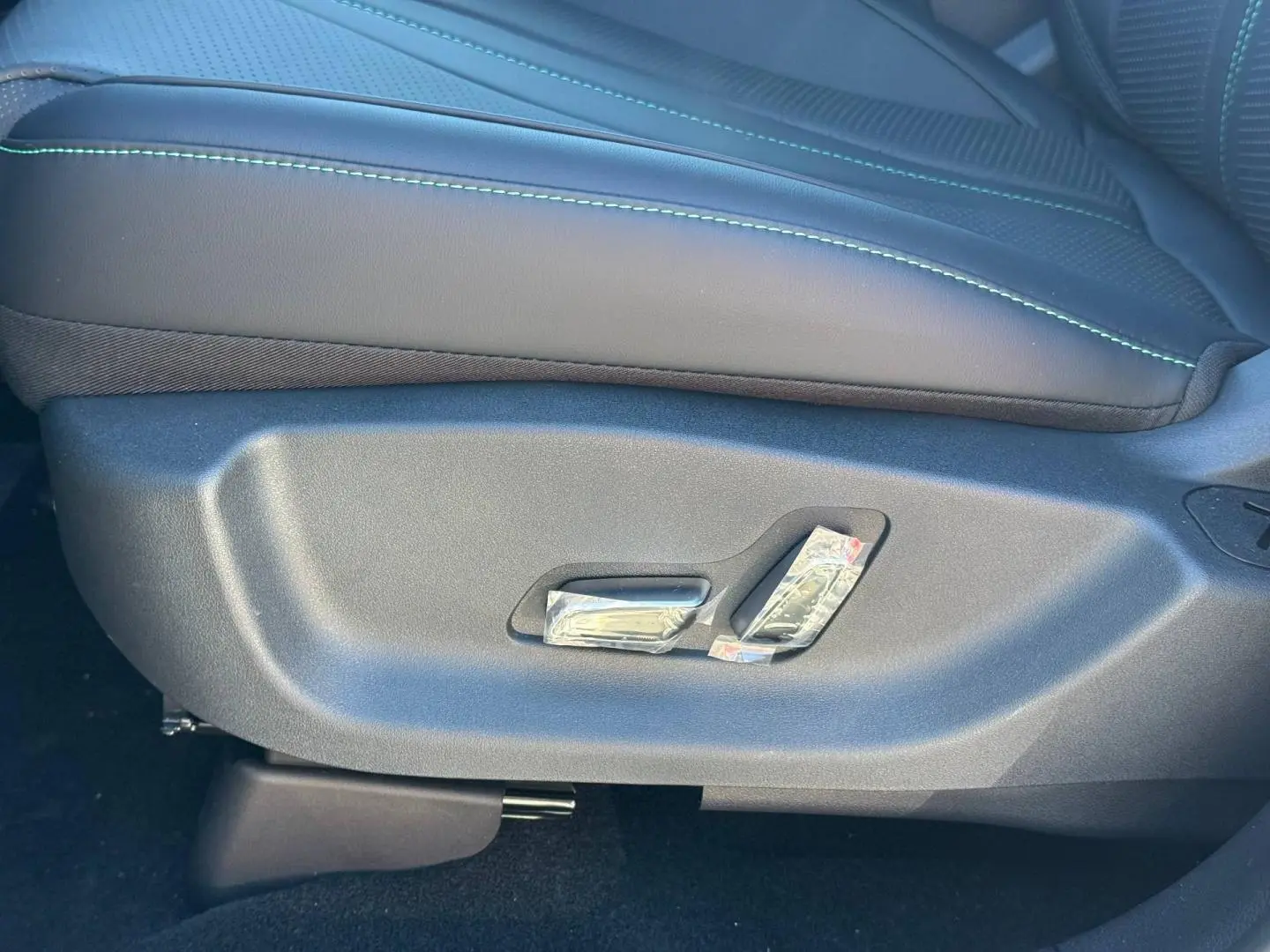 Gros plan sur les commandes de réglage électrique du siège conducteur en cuir noir avec surpiqûres vertes du BYD SEAL U 2026.