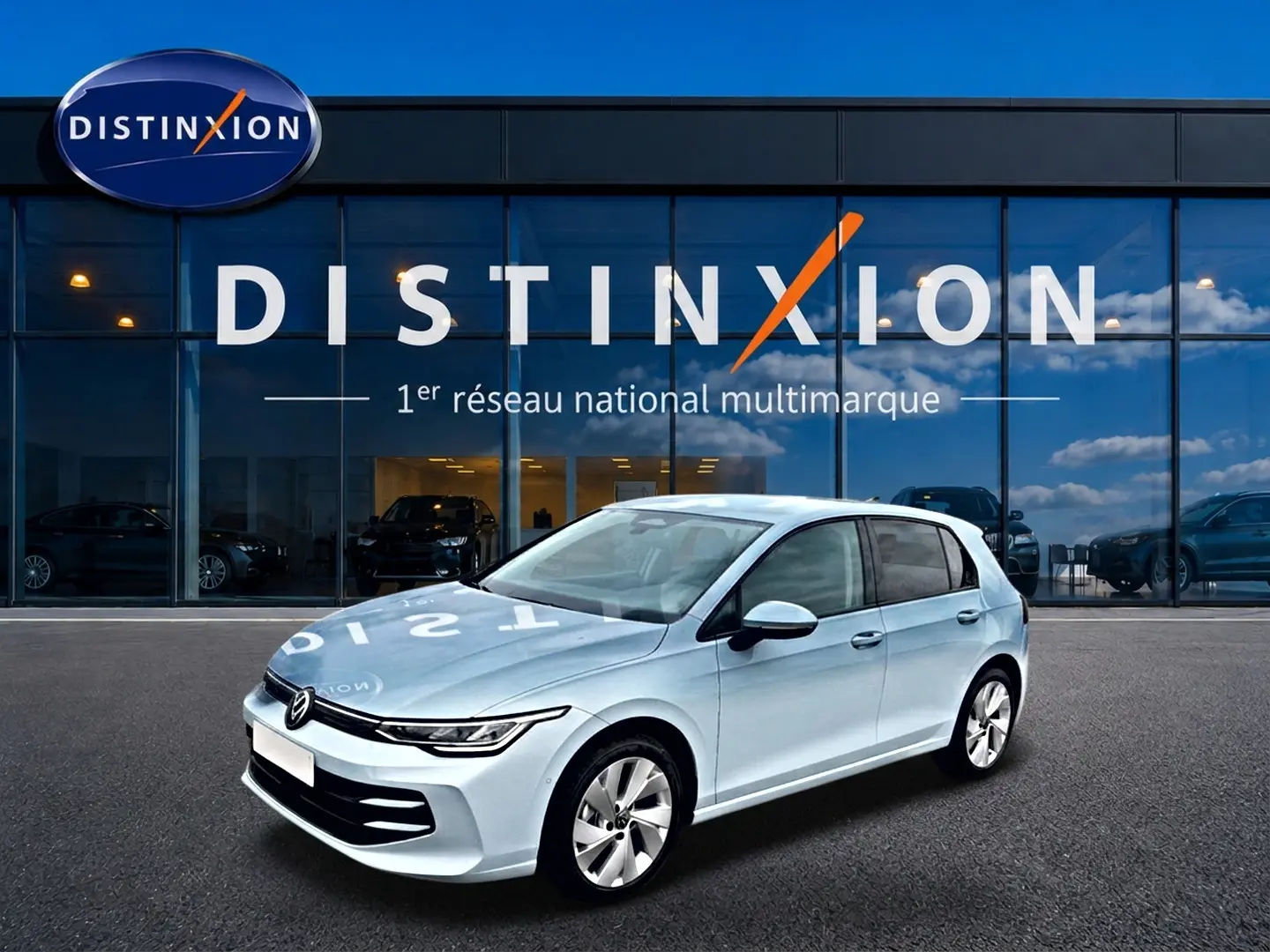 Volkswagen Golf 2026 bleu glacier vue 3/4 avant droit devant vitrine Distinxion avec reflets sur carrosserie.