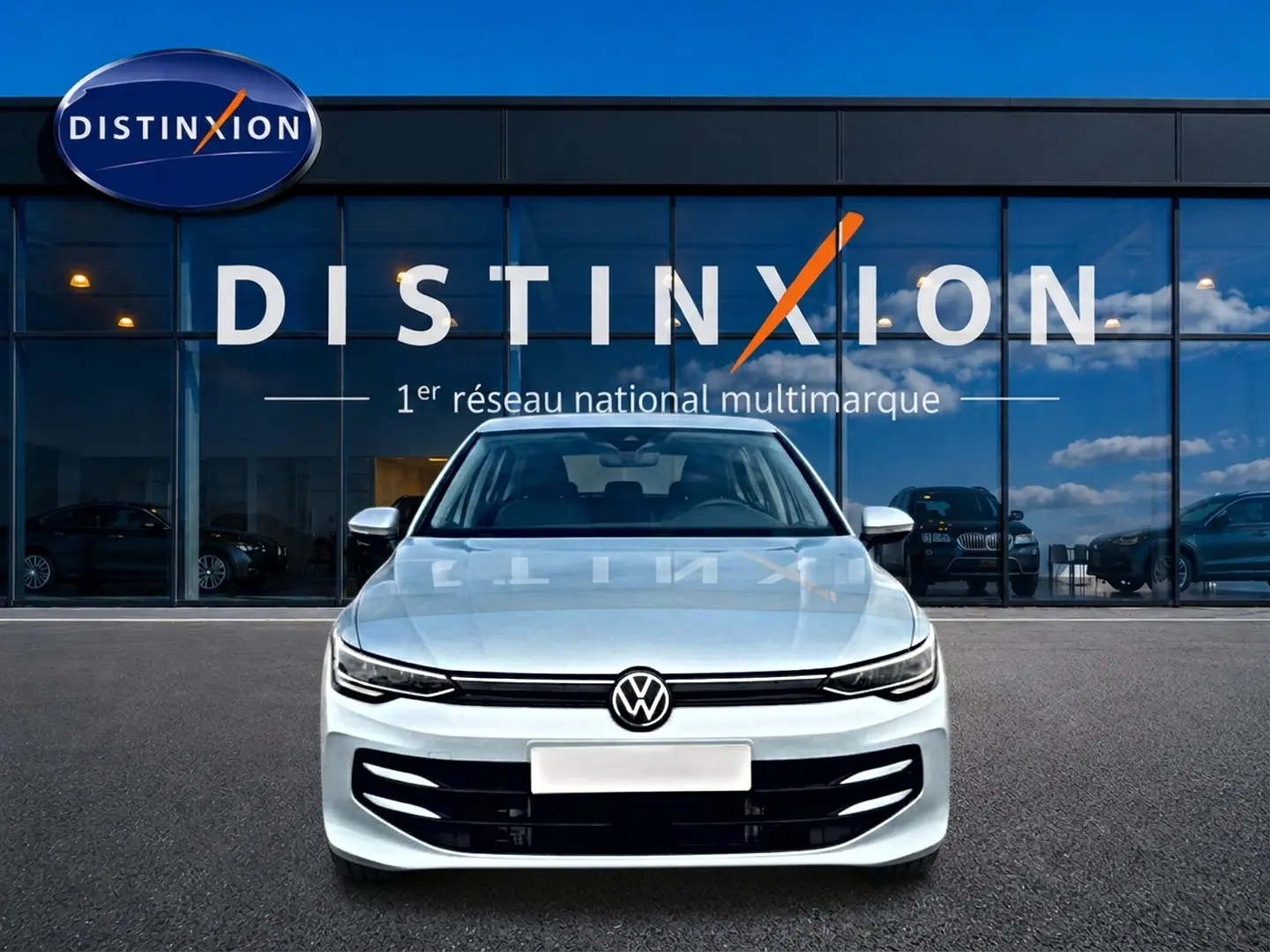 Vue avant d'une Volkswagen Golf 1.5 etsi evo2 116 life dsg7 bleu glacier, devant une vitrine avec logo Distinxion.