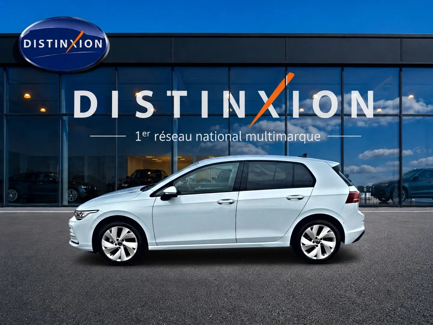 Volkswagen Golf 2026 bleu glacier vue de profil côté gauche devant une vitrine avec logo Distinxion.