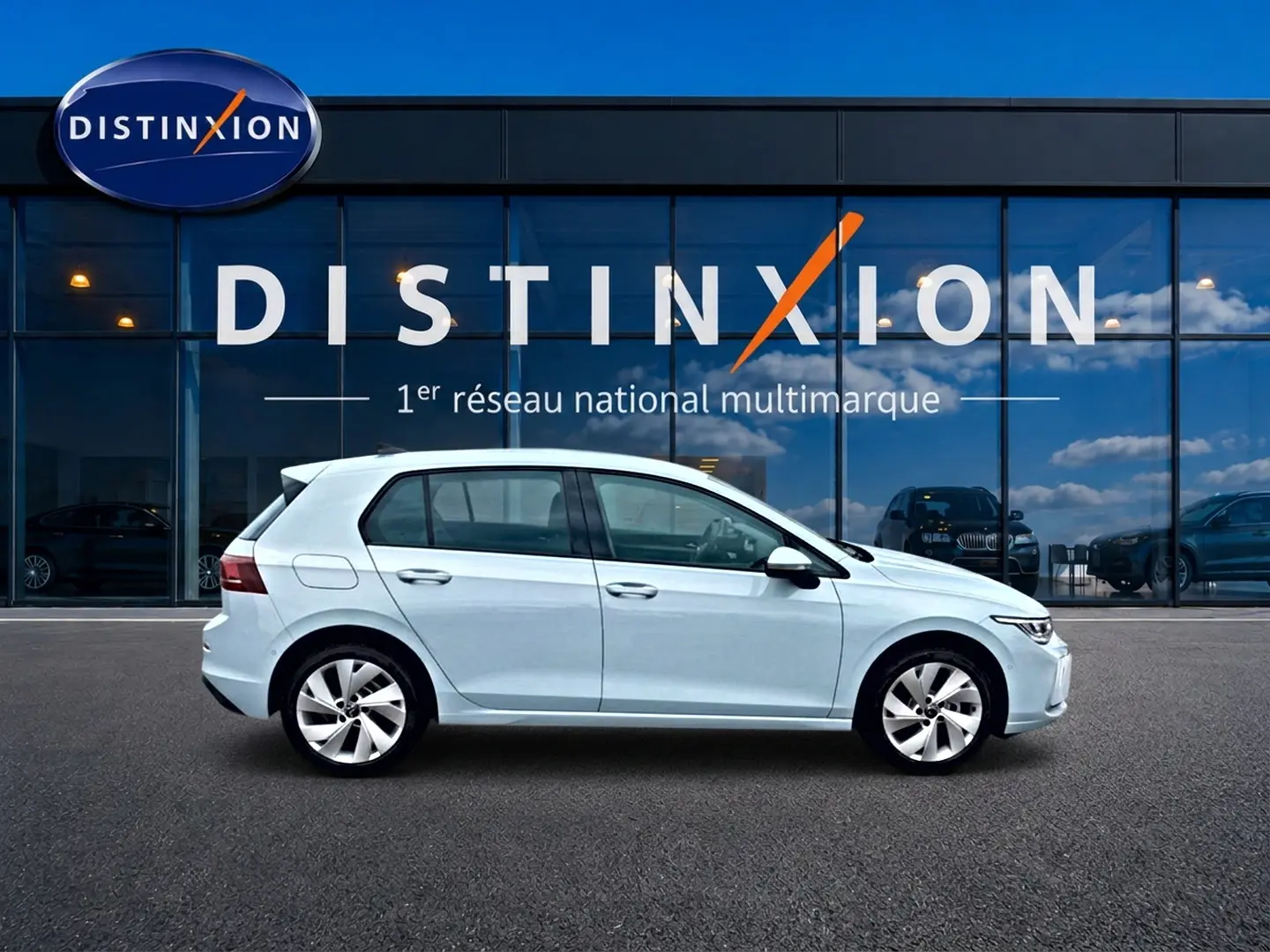 Vue latérale droite d'une Volkswagen Golf 1.5 etsi evo2 116 life dsg7 bleu glacier stationnée devant une vitrine Distinxion.