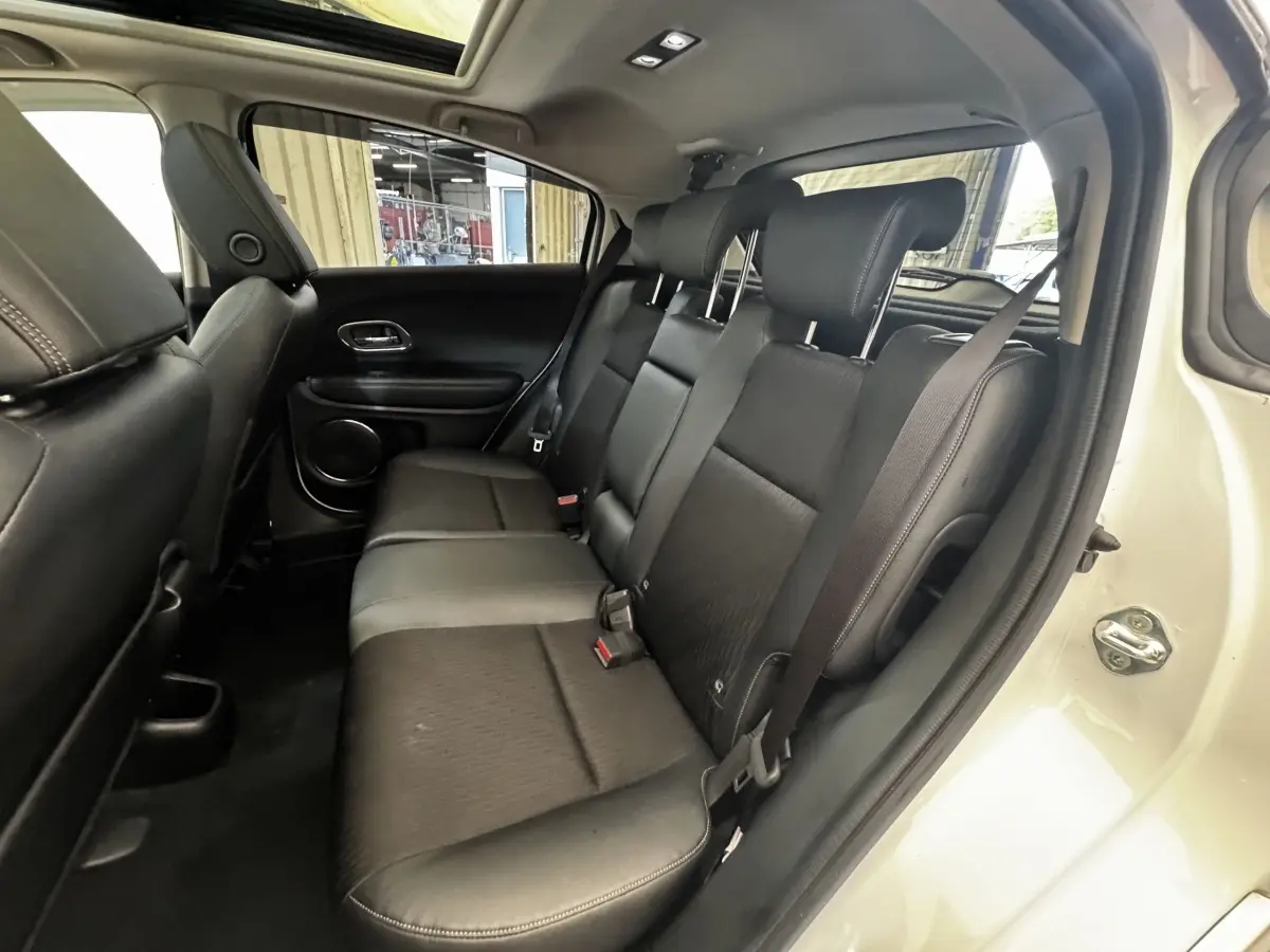 Vue intérieure côté droit sur la banquette arrière en cuir noir du Honda HR-V blanc, avec ceinture de sécurité attachée.
