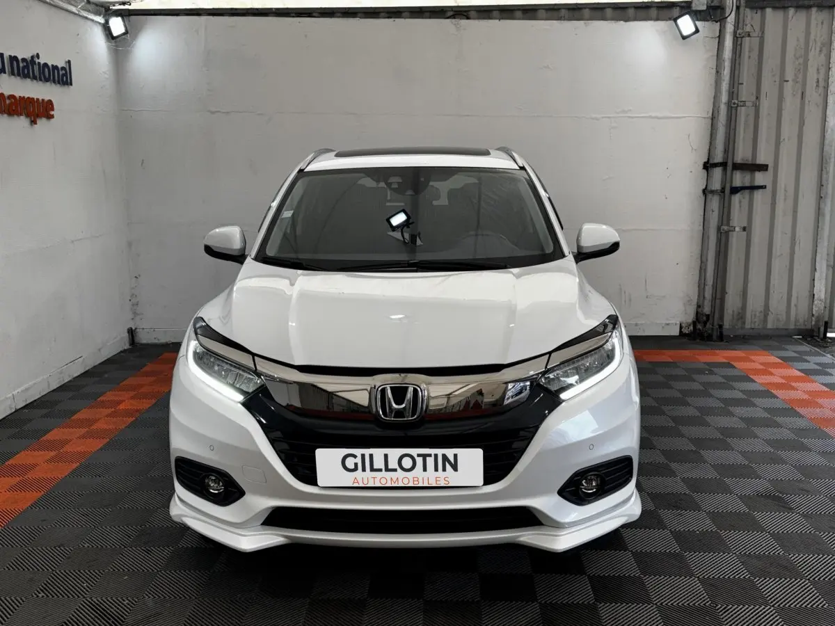 Vue avant d'un Honda HR-V blanc 2019 avec calandre chromée et feux LED allumés dans un showroom.