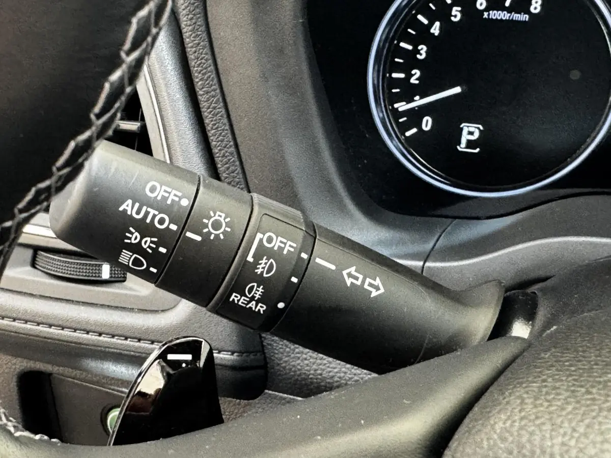 Gros plan sur la commande des phares et clignotants du tableau de bord noir du Honda HR-V blanc.