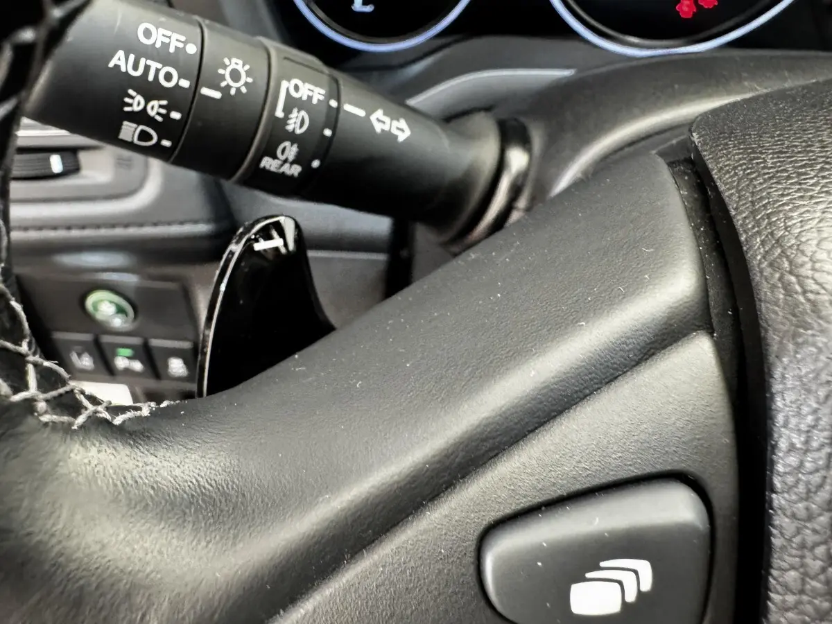 Gros plan sur le volant noir et la commande des phares du tableau de bord du Honda HR-V 1.5 i-VTEC 130 Exclusive 2019.