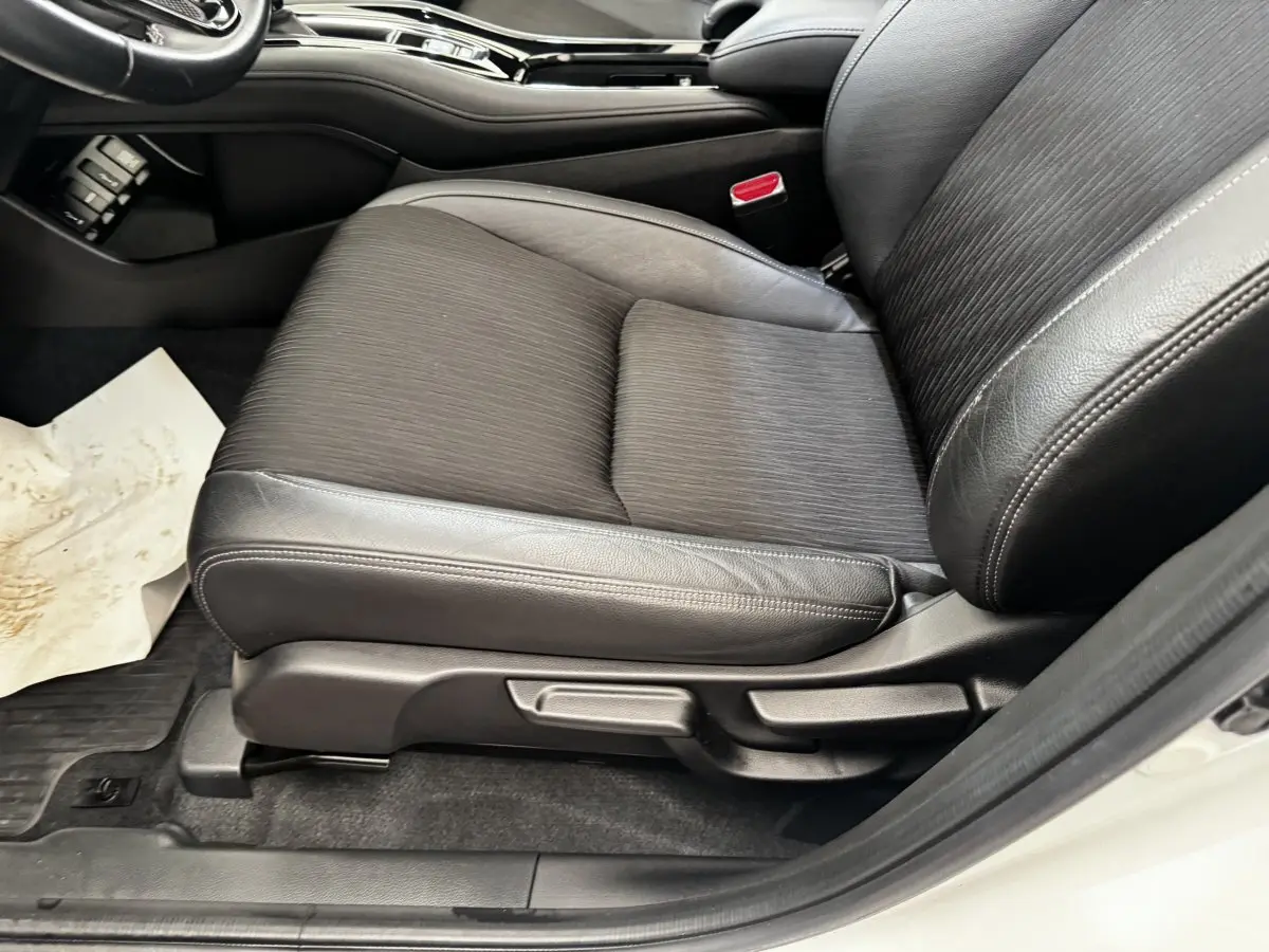Gros plan sur le siège avant droit noir en cuir et tissu du Honda HR-V blanc, avec réglages manuels visibles.
