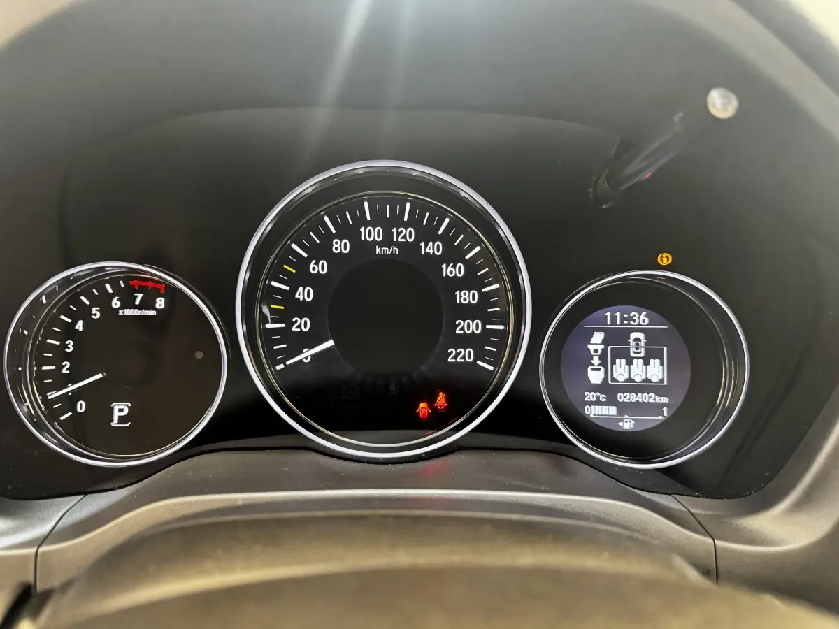 Vue rapprochée du tableau de bord du Honda HR-V blanc, affichant la vitesse, le compte-tours et un écran digital multifonctions.
