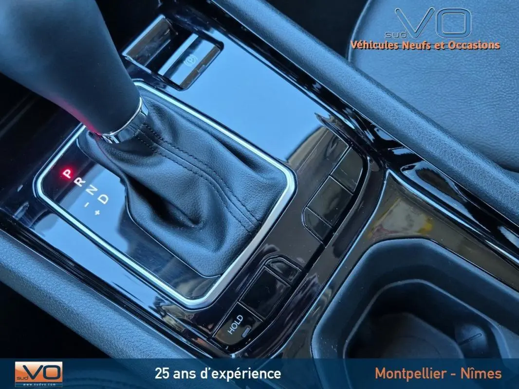 Gros plan sur la console centrale noire brillante du Jeep Compass gris 2024 avec levier de vitesse automatique et accoudoir.