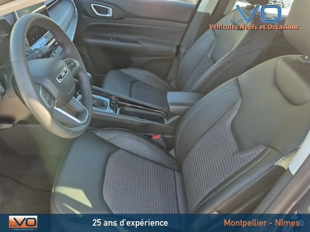 Vue intérieure côté conducteur du Jeep Compass 2024, sièges noirs avec accoudoir central et volant multifonction.